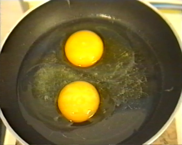 Sala Professori. Il Bidello sta cuocendo due uova al tegamino sul suo fornelletto.